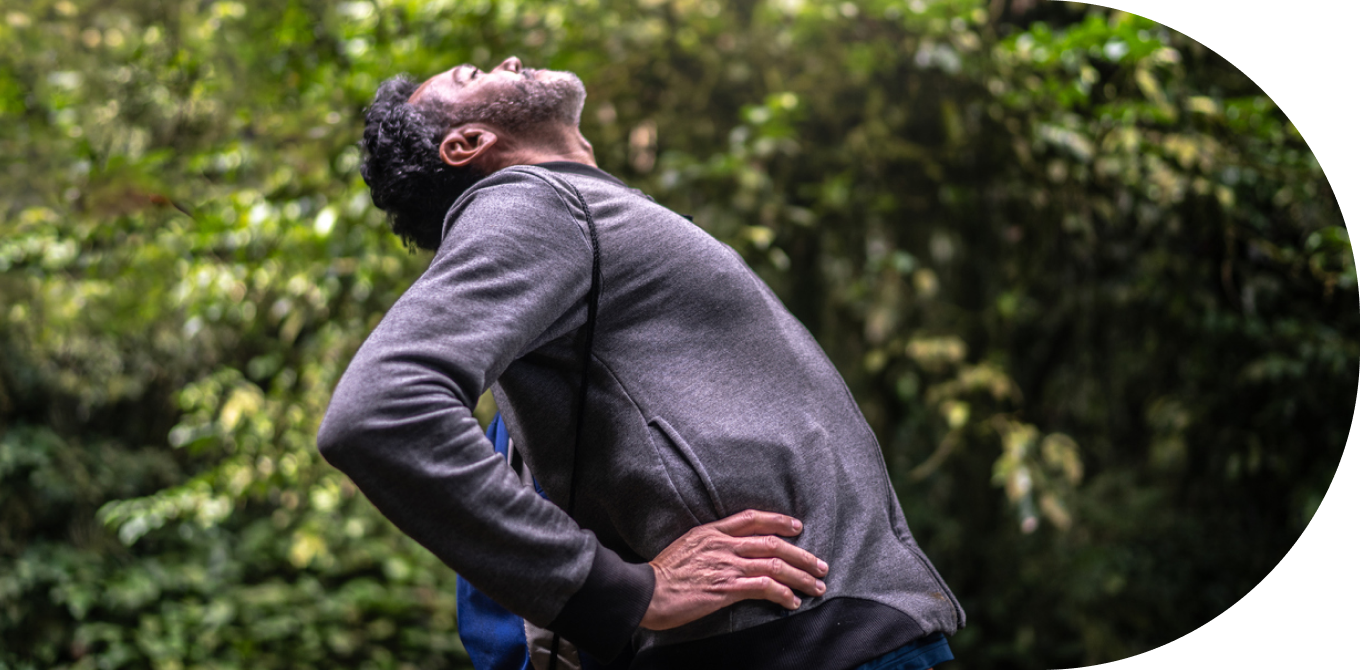 Homem experimentando dor nas costas e se alongando no parque
